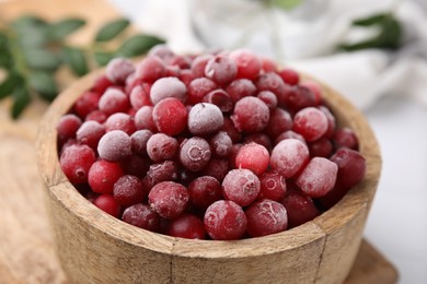 Frozen red cranberries in bowl on table, closeup