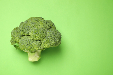 Fresh broccoli on green background, top view. Space for text