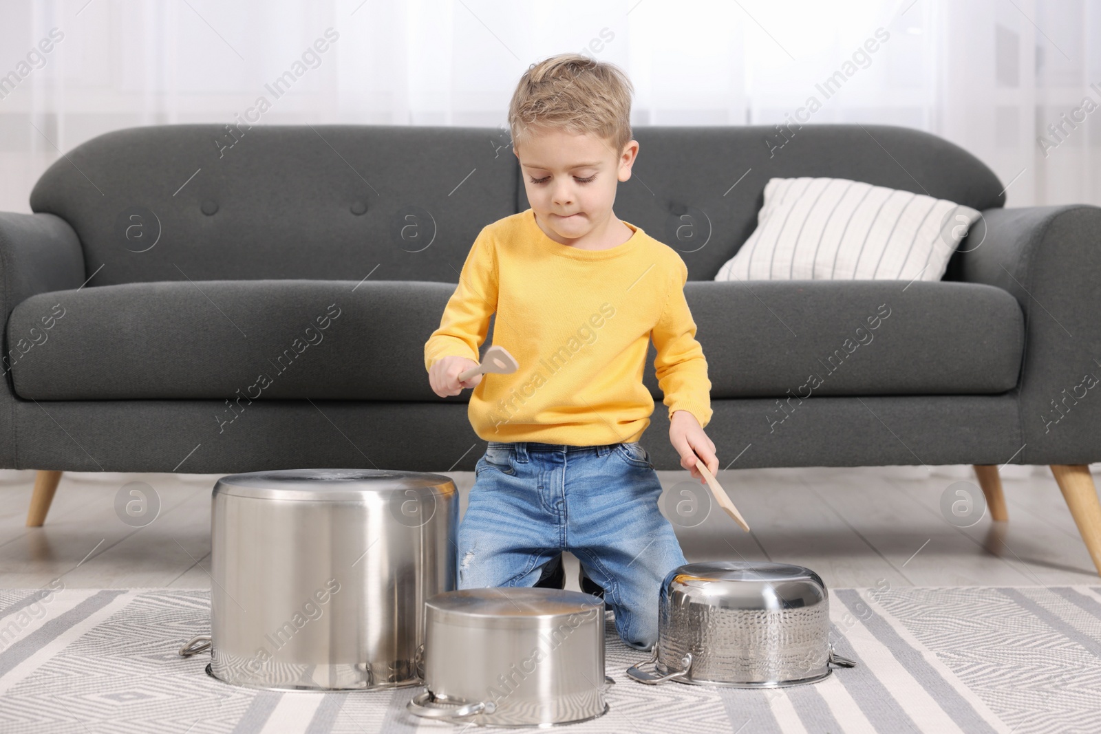 Photo of Little boy pretending to play drums on pots at home