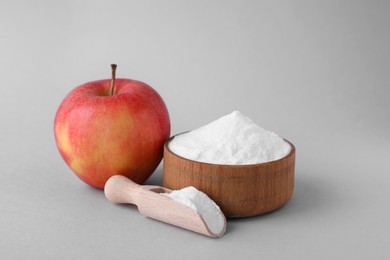 Photo of Bowl, scoop with sweet fructose powder and ripe apple on white background