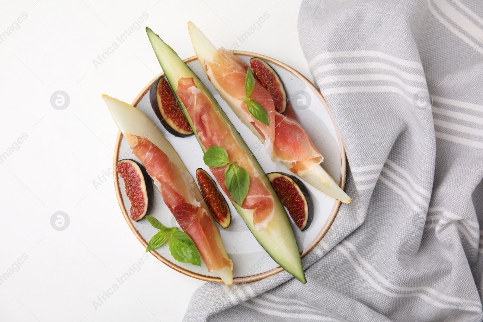 Photo of Plate of tasty melon, jamon, and figs on white table, top view