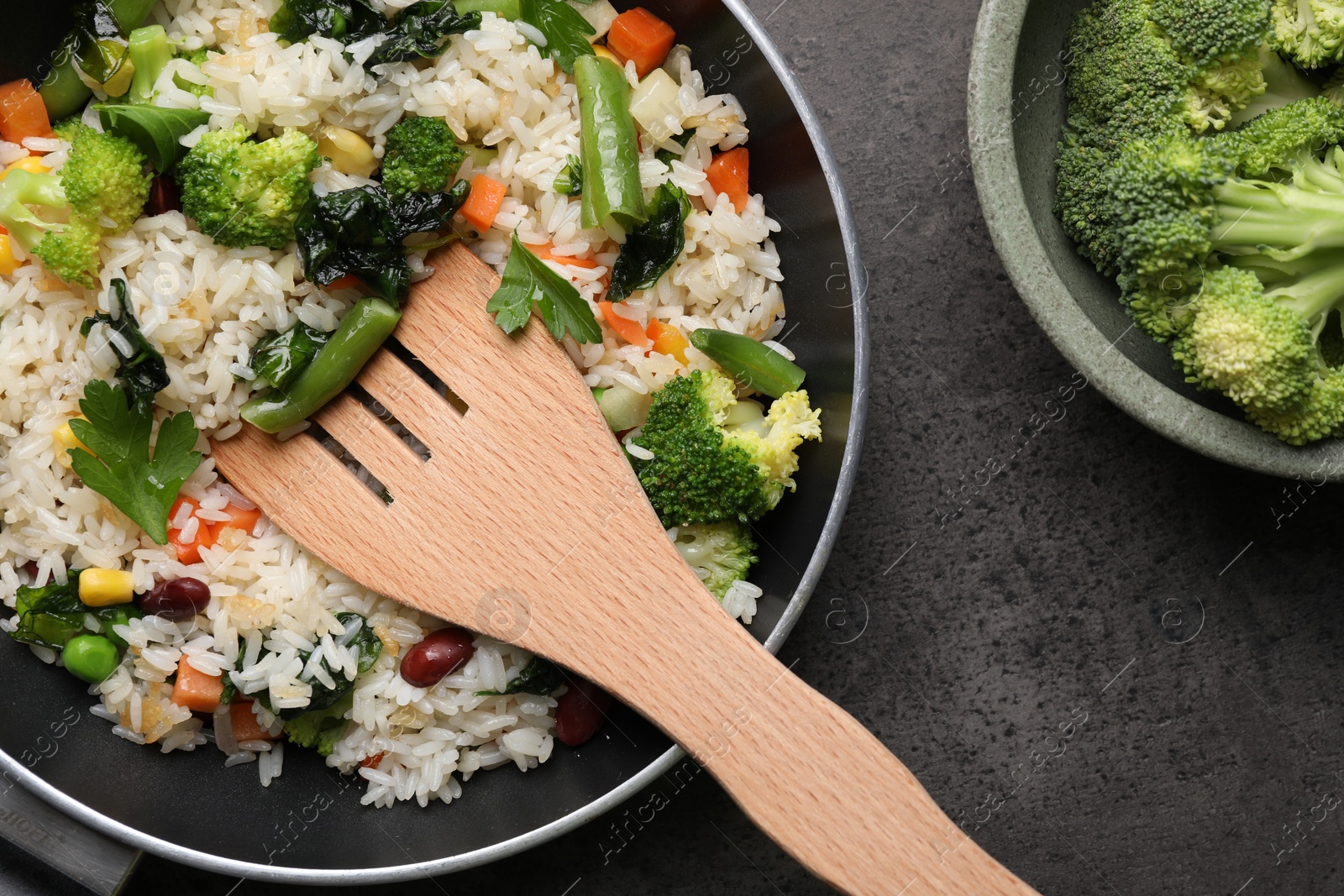 Photo of Tasty fried rice with vegetables served on black table, flat lay