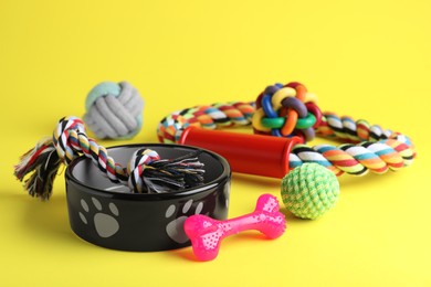 Photo of Feeding bowls and toys for pet on yellow background