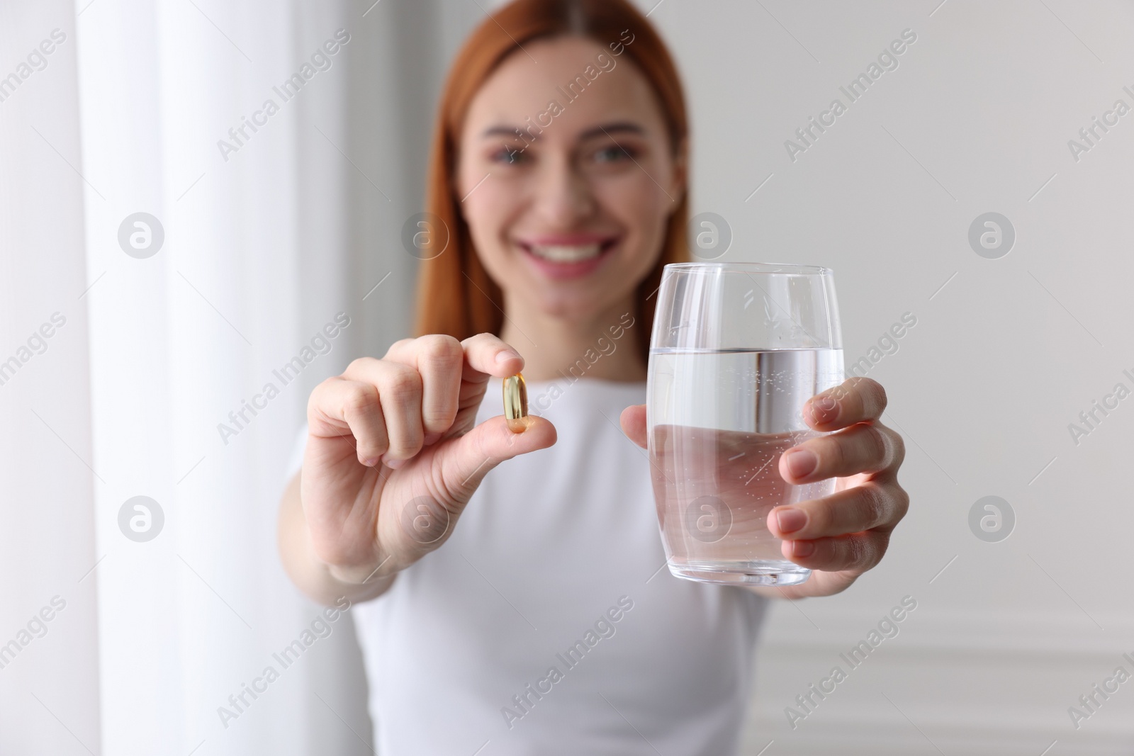 Photo of Beautiful young woman with vitamin pill and glass of water, selective focus