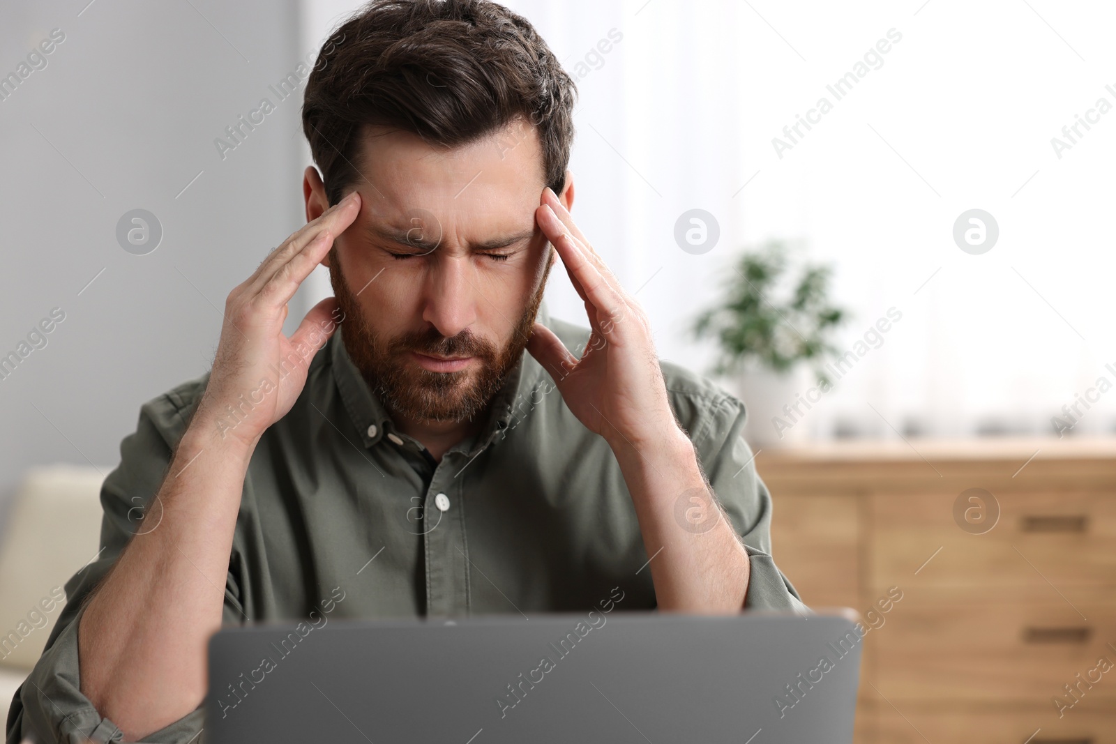 Photo of Tired man suffering from headache indoors. Space for text