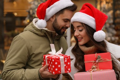 Lovely couple with Christmas presents near festively decorated store outdoors