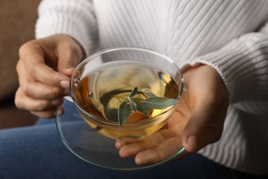 Photo of Woman drinking tasty herbal tea, closeup view