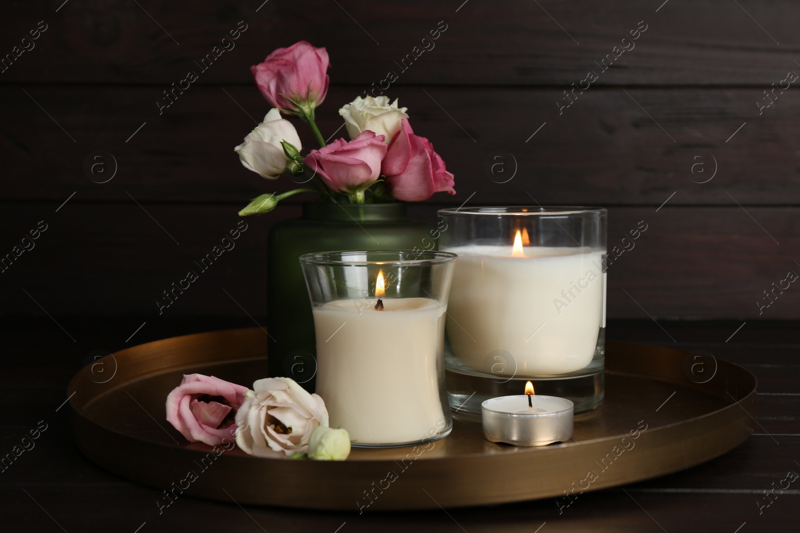 Photo of Beautiful composition with burning candles and roses on wooden table