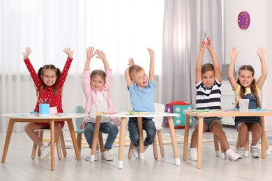 Photo of Group of cute little children having fun at tables in kindergarten. Playtime activities