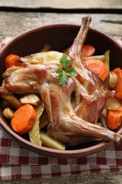 Photo of Tasty cooked rabbit with vegetables in bowl on wooden table, closeup