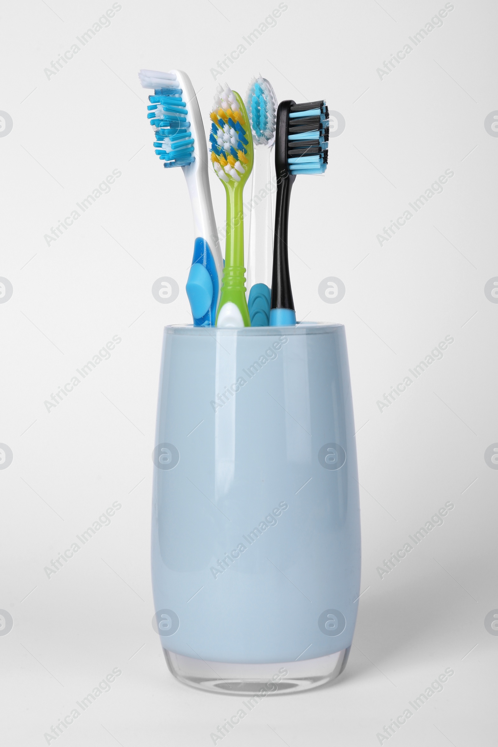 Photo of Different toothbrushes in holder on light grey background