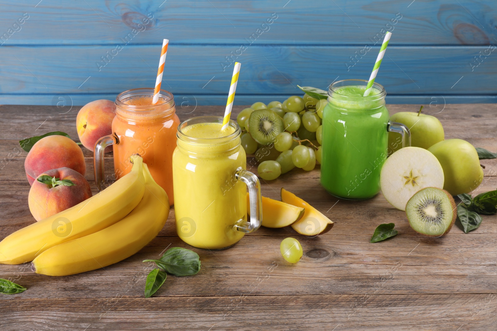 Photo of Mason jars of different tasty smoothies and fresh ingredients on wooden table