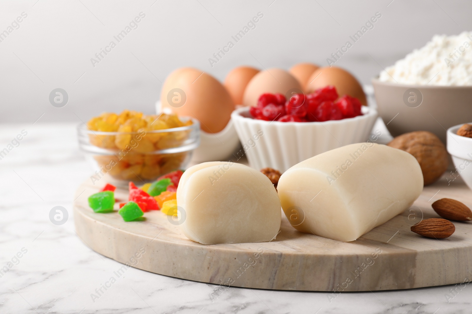 Photo of Marzipan and other ingredients for homemade Stollen on white marble table, closeup. Baking traditional German Christmas bread