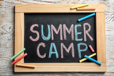 Text "SUMMER CAMP" on small blackboard and colorful chalk, top view