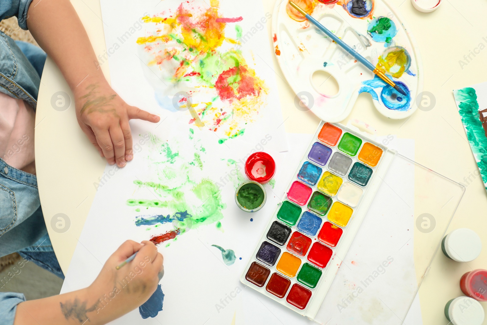 Photo of Little child painting at light table, top view