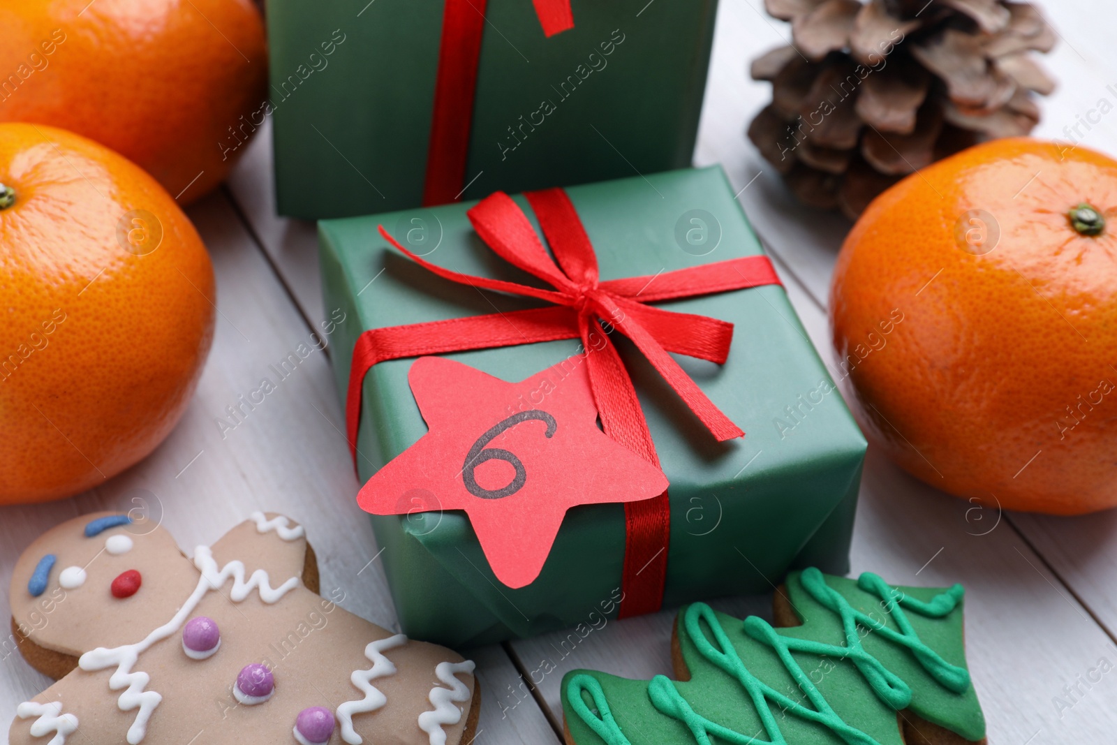 Photo of Gift boxes with paper tag and treats on white wooden background. December, 6 - Saint Nicholas Day