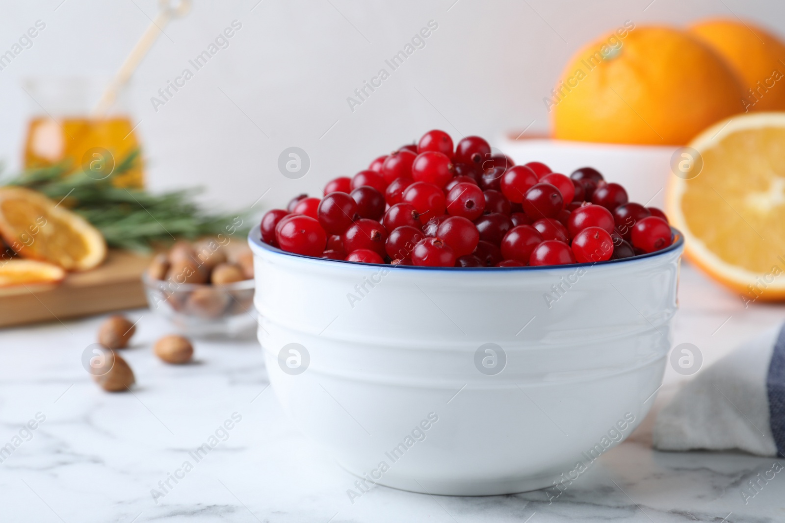 Photo of Fresh ripe cranberries in bowl on white marble table. Space for text