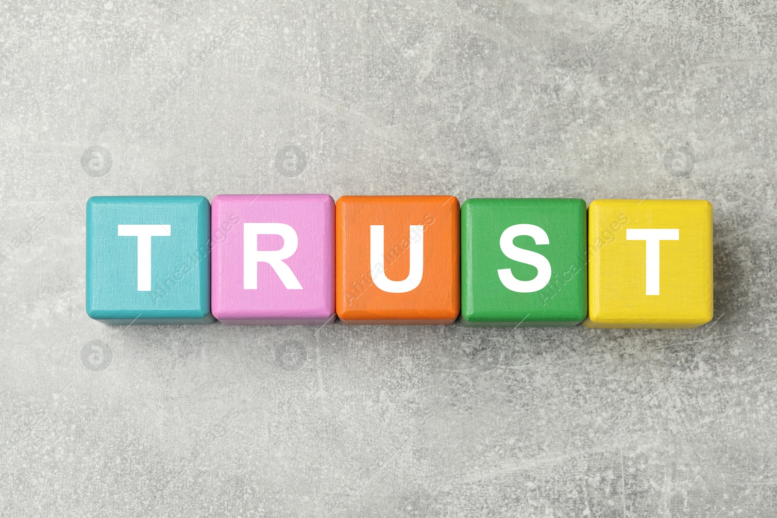 Photo of Word Trust made of colorful cubes on light grey table, flat lay