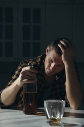 Photo of Addicted man with alcoholic drink at table in kitchen