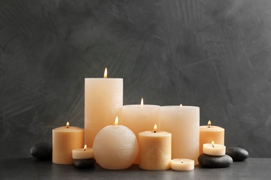 Beautiful composition with lit candles and spa stones on table