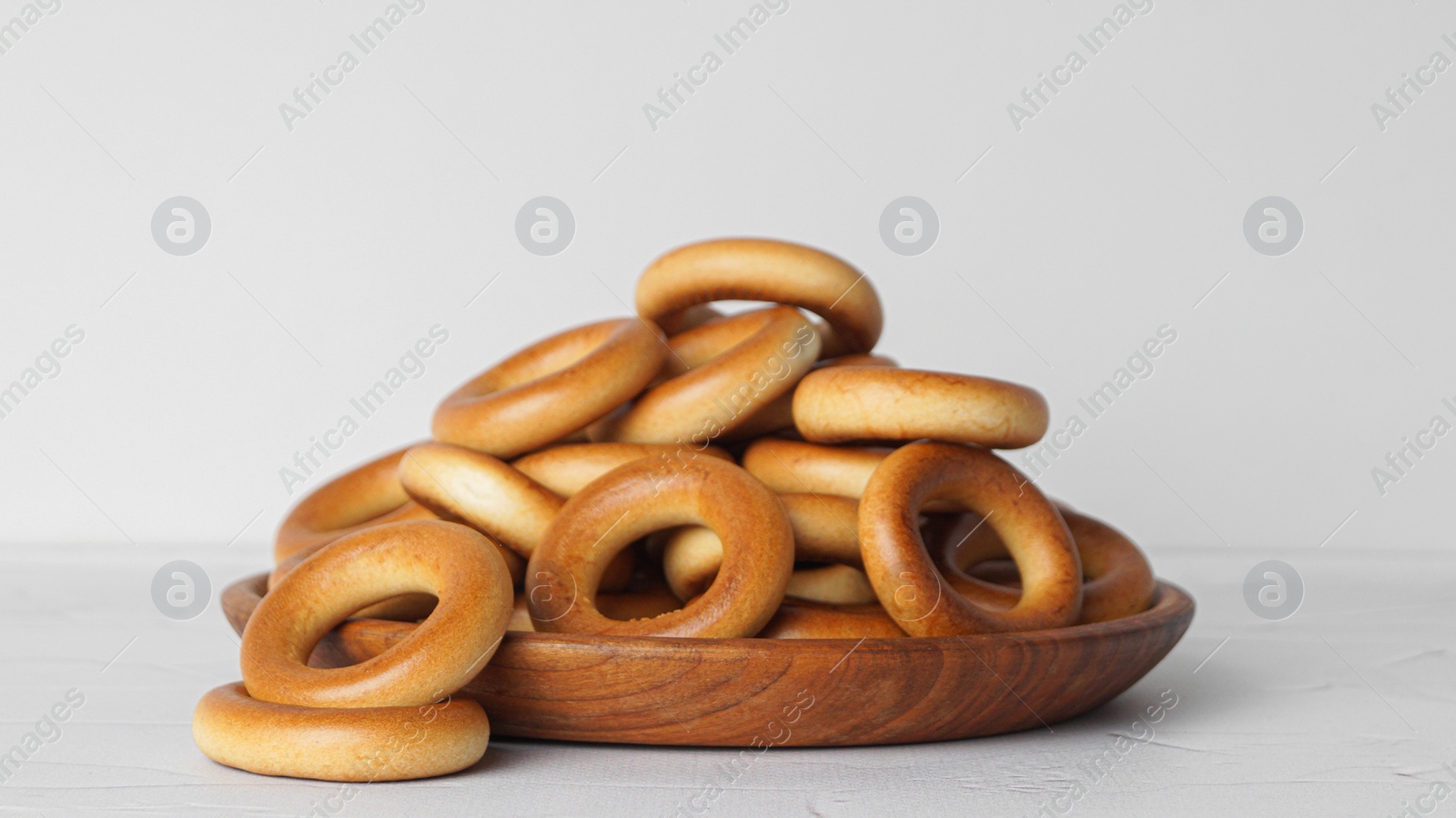 Photo of Plate with tasty dry bagels (sushki) on white textured table