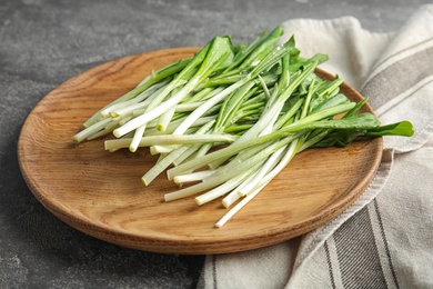 Wooden plate with wild garlic or ramson on grey table