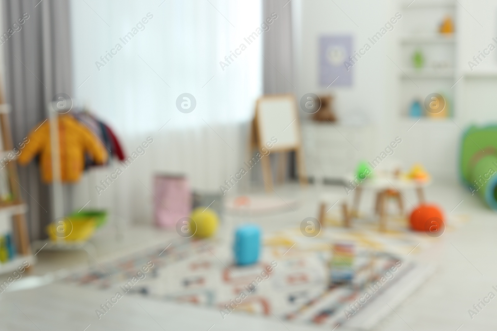 Photo of Blurred view of child`s playroom with different toys and furniture. Stylish kindergarten interior