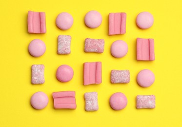 Photo of Pink bubble gums on yellow background, flat lay