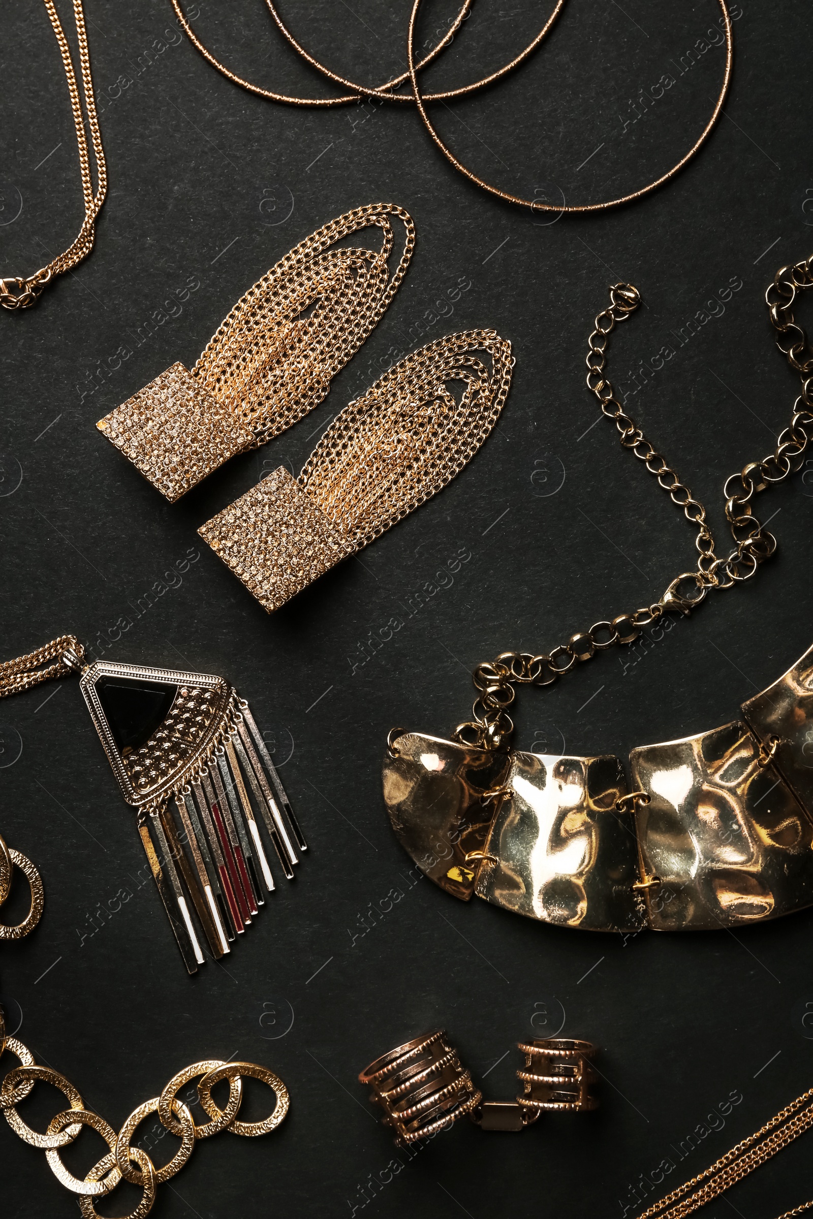 Photo of Set of gold jewelry on black background, flat lay