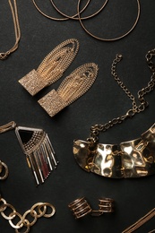 Photo of Set of gold jewelry on black background, flat lay