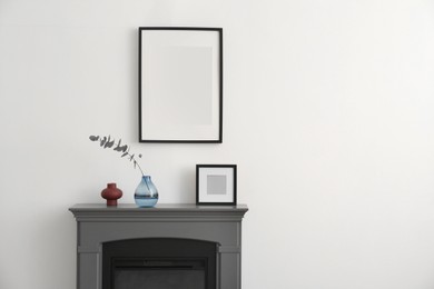 Photo of Fireplace, decorative elements and photo frames in room with white wall, space for text. Interior design