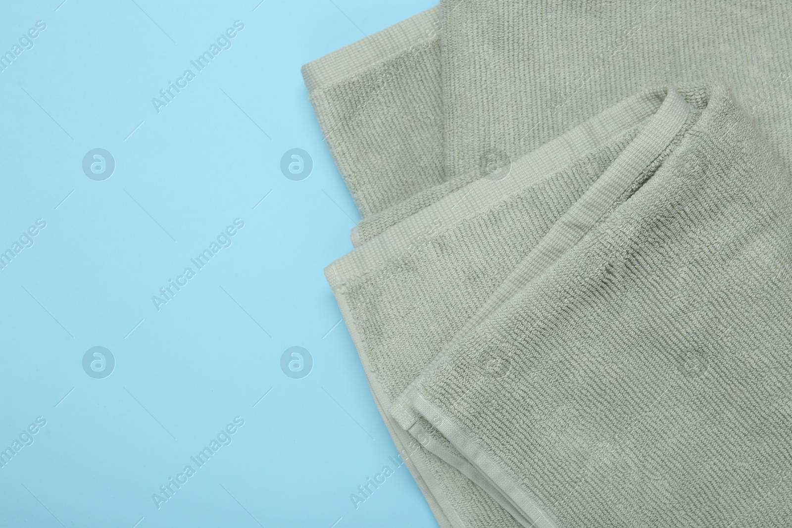 Photo of Terry towels on light blue background, top view. Space for text