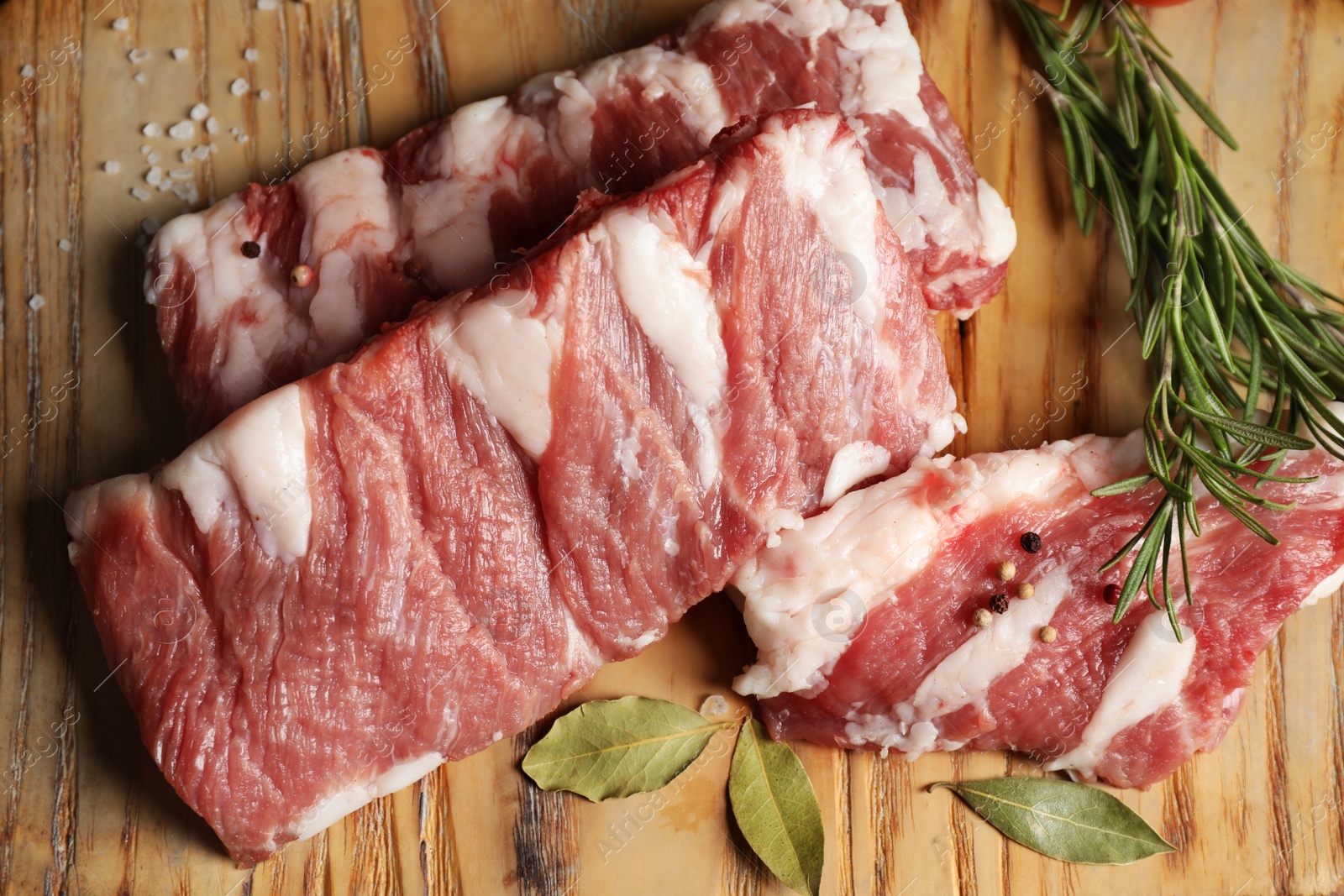 Photo of Raw ribs with herbs and spices on wooden table, flat lay