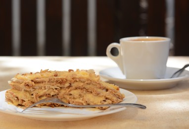 Piece of delicious cake and coffee on beige table in cafe, closeup