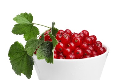 Tasty ripe redcurrants and green leaves in bowl isolated on white