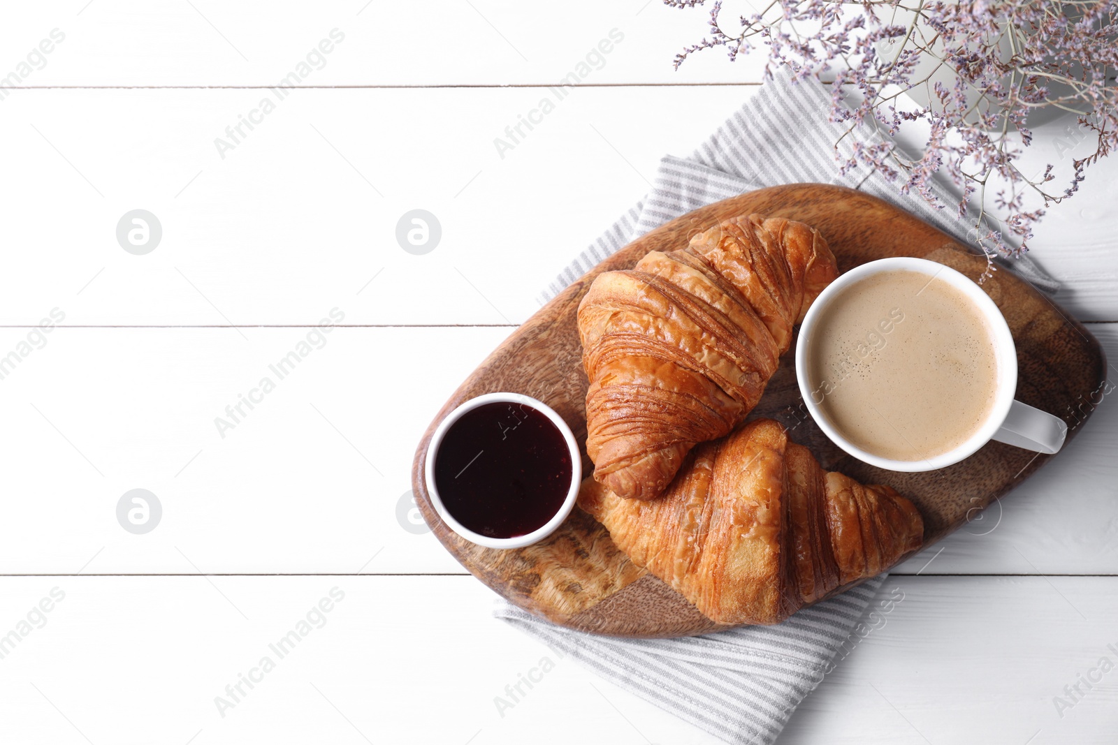 Photo of Tasty breakfast. Cup of coffee, jam and croissants on white wooden table, top view. Space for text