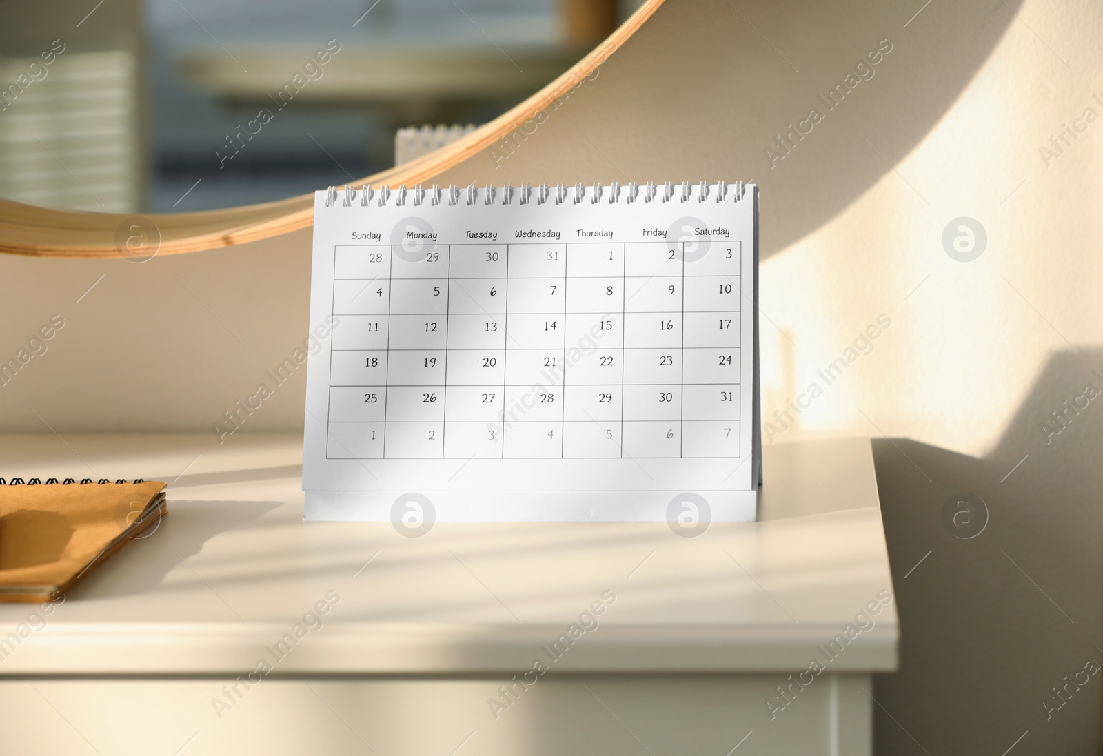 Photo of Paper calendar on white chest of drawers indoors