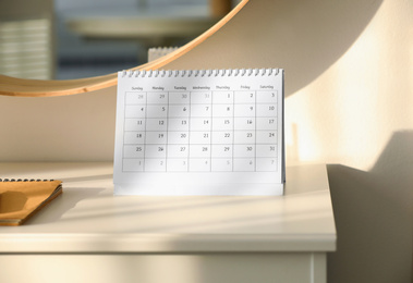 Paper calendar on white chest of drawers indoors