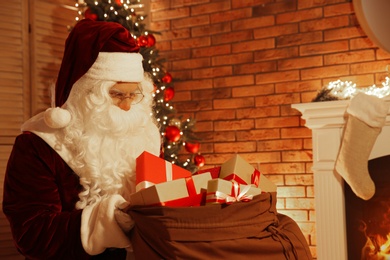 Photo of Santa Claus with sack of gifts in festively decorated room