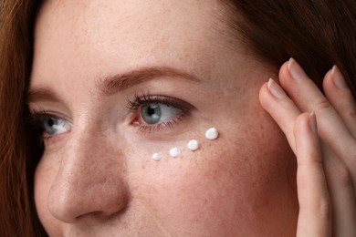 Photo of Beautiful woman with freckles and cream on her face, closeup