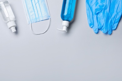 Photo of Medical gloves, mask and hand sanitizers on grey background, flat lay. Space for text