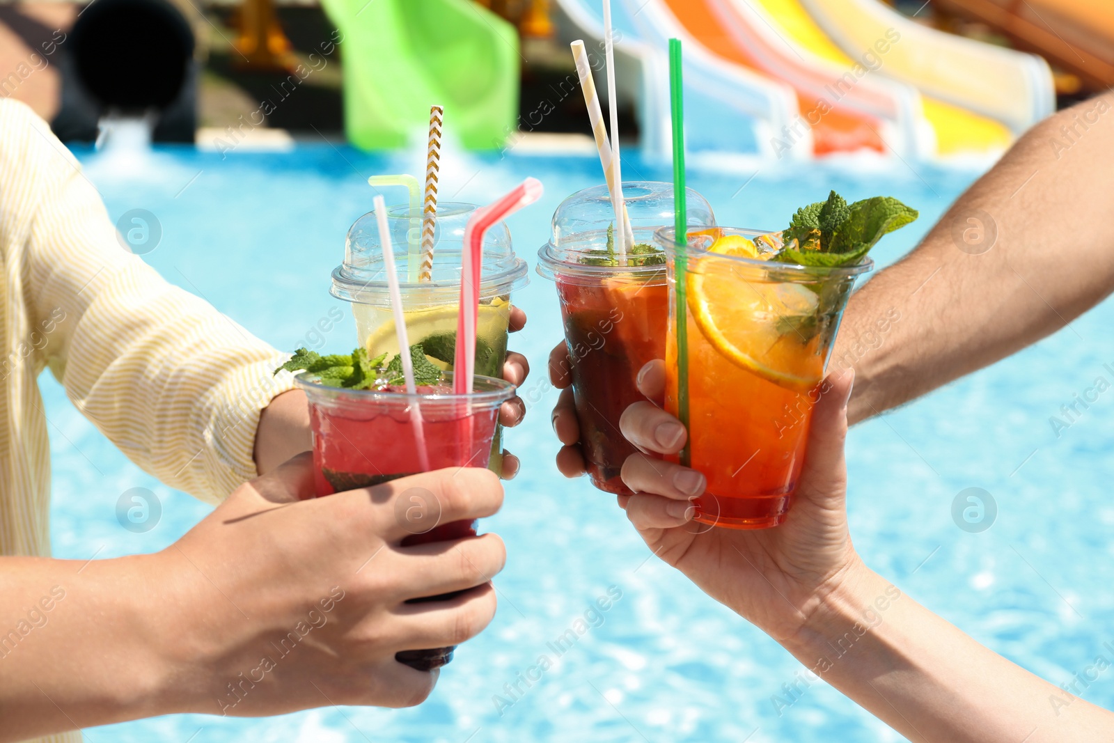 Photo of People with refreshing drinks in water park, closeup