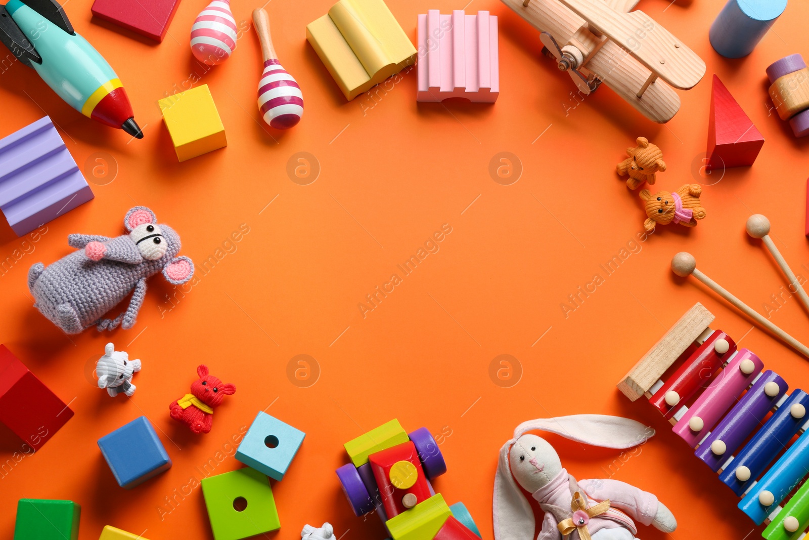Photo of Frame of different toys on orange background, flat lay. Space for text