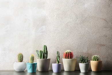 Different potted cacti on table near color background, space for text. Interior decor