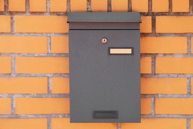 Photo of Black metal letter box on red brick wall