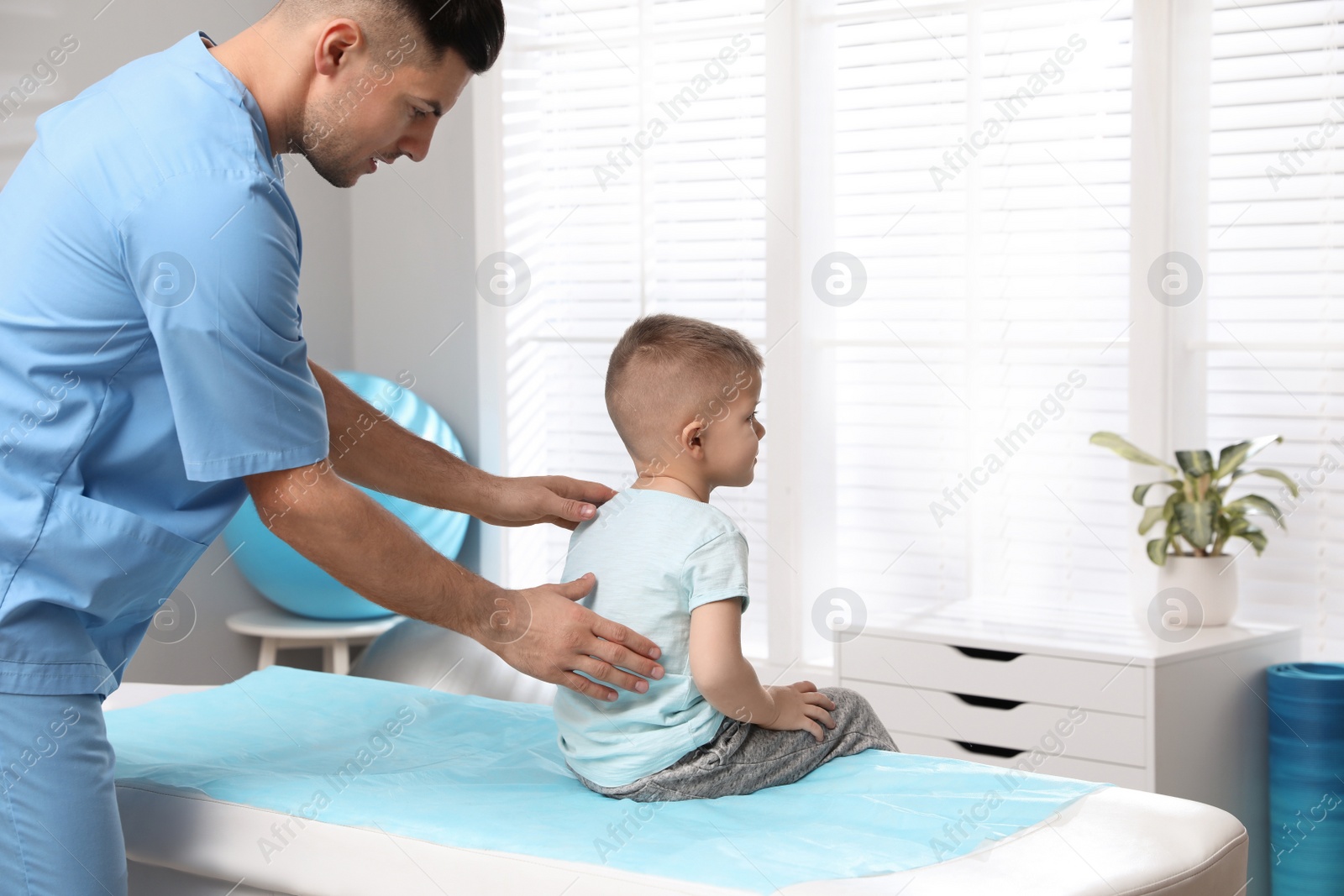 Photo of Orthopedist examining child's back in clinic. Scoliosis treatment