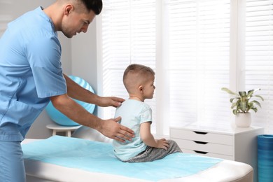 Photo of Orthopedist examining child's back in clinic. Scoliosis treatment