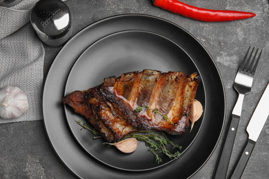 Photo of Tasty grilled ribs served on grey table, flat lay
