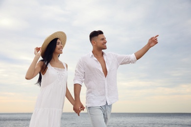 Lovely couple holding hands while walking near sea