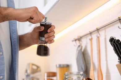Photo of Man using manual coffee grinder in kitchen, closeup. Space for text